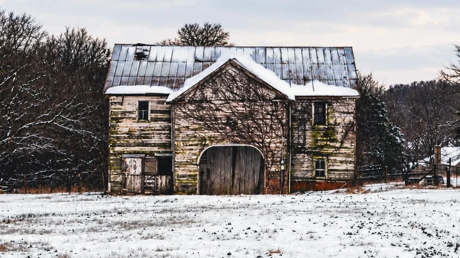 Weathered barn surrounded by snow in winter