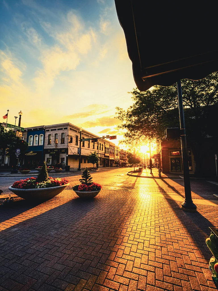 A downtown street glowing in warm golden-hour light.